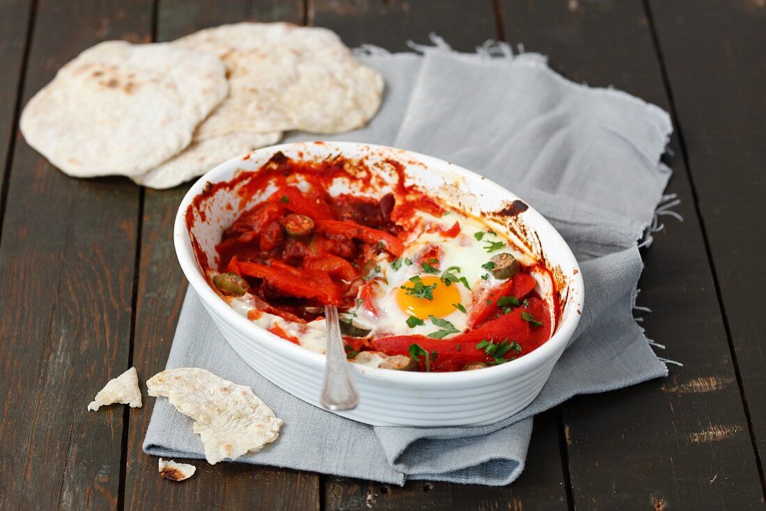Oven-baked eggs in tomato sauce with peppers served with tortillas