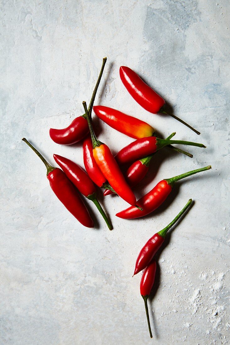 Red chilli peppers on a white surface (seen from above)