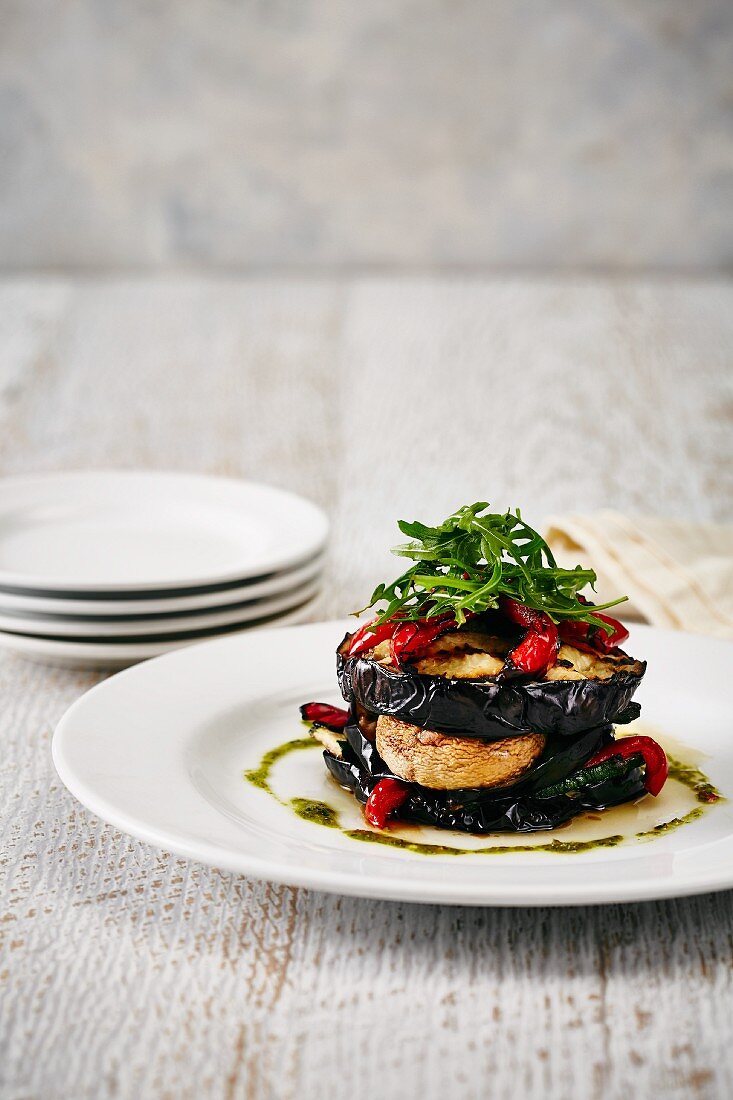 A stack of vegetables with aubergines, peppers and rocket
