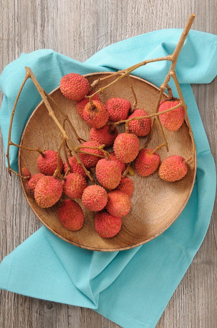 Lychees on twigs on a wooden plate