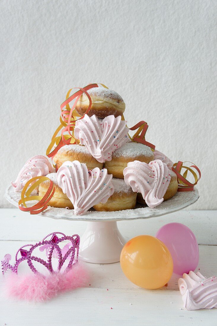 Krapfen mit rosa Baiserherzen, Faschingskrone, Luftschlangen und Luftballons