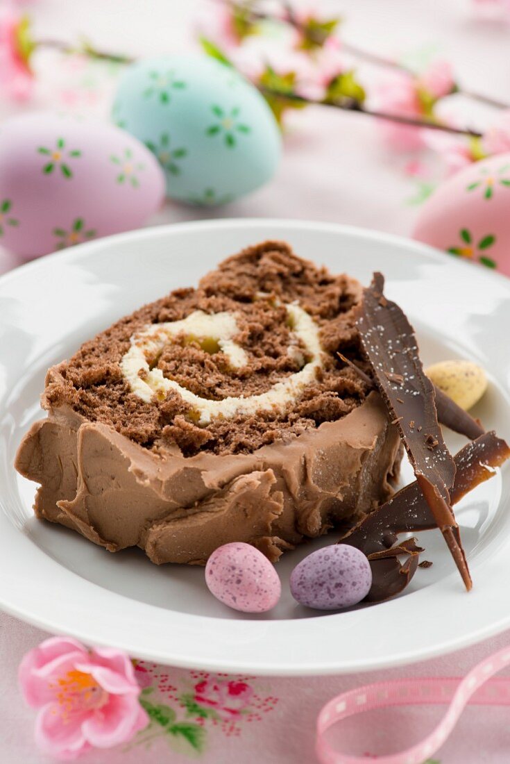 A slice of Easter chocolate log cake with chocolate cream and Easter eggs