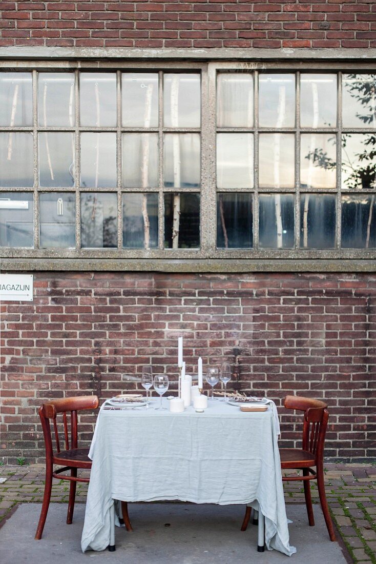 Rustikal gedeckter Tisch vor einer Fabrikfassade