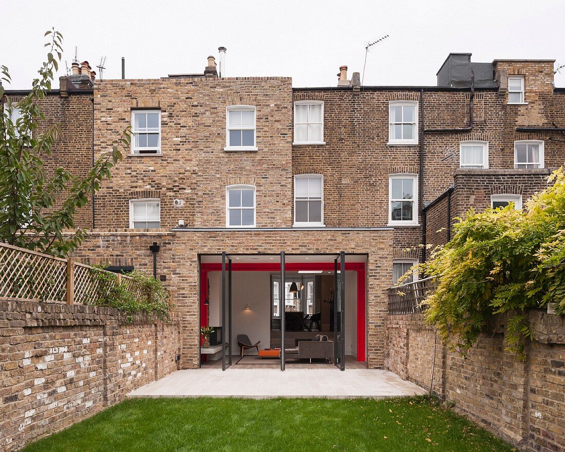 View from courtyard; traditional English brick house with open terrace doors and extension