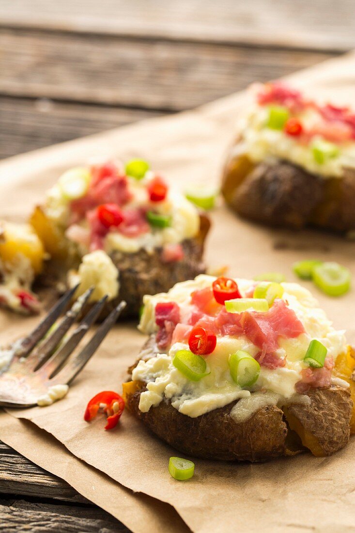 Überbackener Stampfkartoffel mit Frischkäse, Speck und Käse, garniert mit Chiliringen und Frühlingszwiebeln