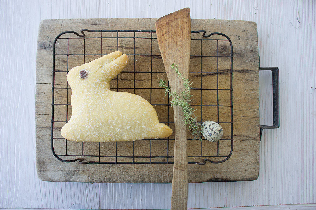 A baked Easter bunny biscuit with a quail egg and a sprig of thyme
