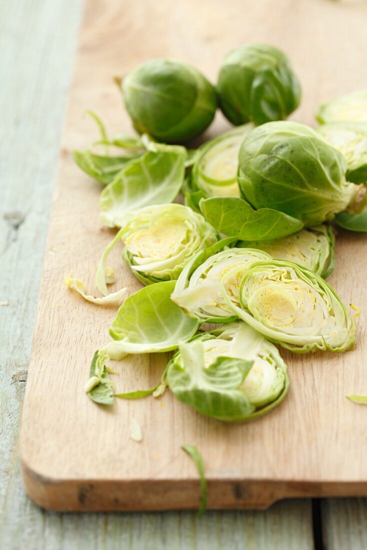Fresh Brussels sprouts, partially sliced, on a wooden board
