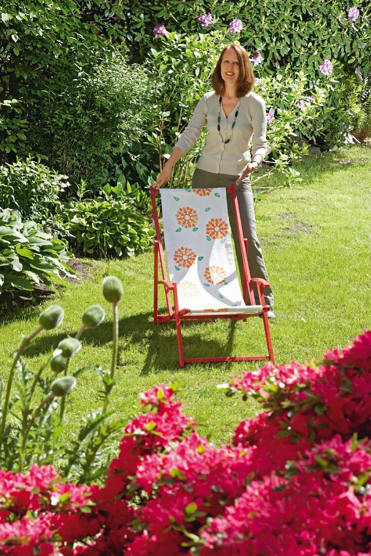 Frau mit aufgemöbeltem Liegestuhl im Garten