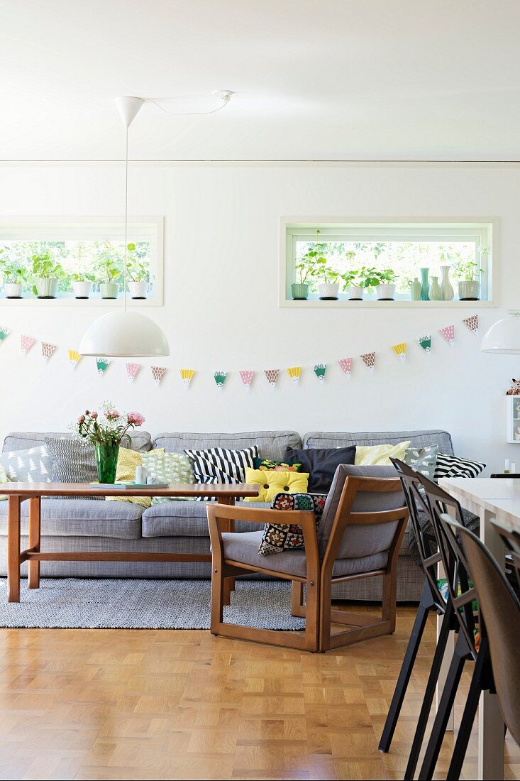 Wooden armchair and matching exotic-wood table below bunting on wall below transom windows