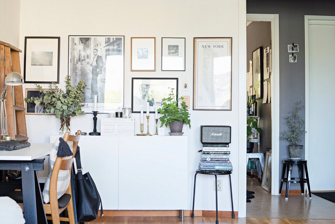 Retro Wohnzimmer mit Arbeitsplatz, im Hintergrund Bildergalerie über weißem Sideboard