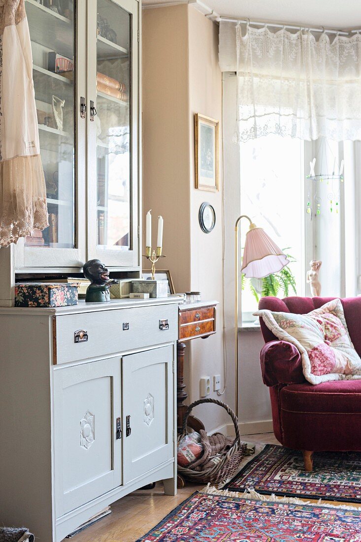 Pale grey dresser and vintage-style standard lamp next to claret-red armchair in window bay