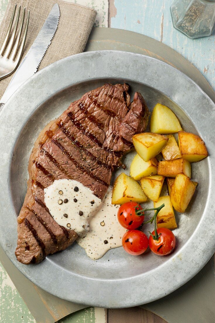 Grilled steak with a pepper sauce and fried potatoes