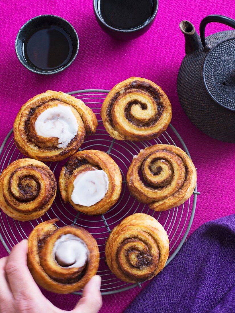 Homemade cinnamon buns with icing on a cooling rack