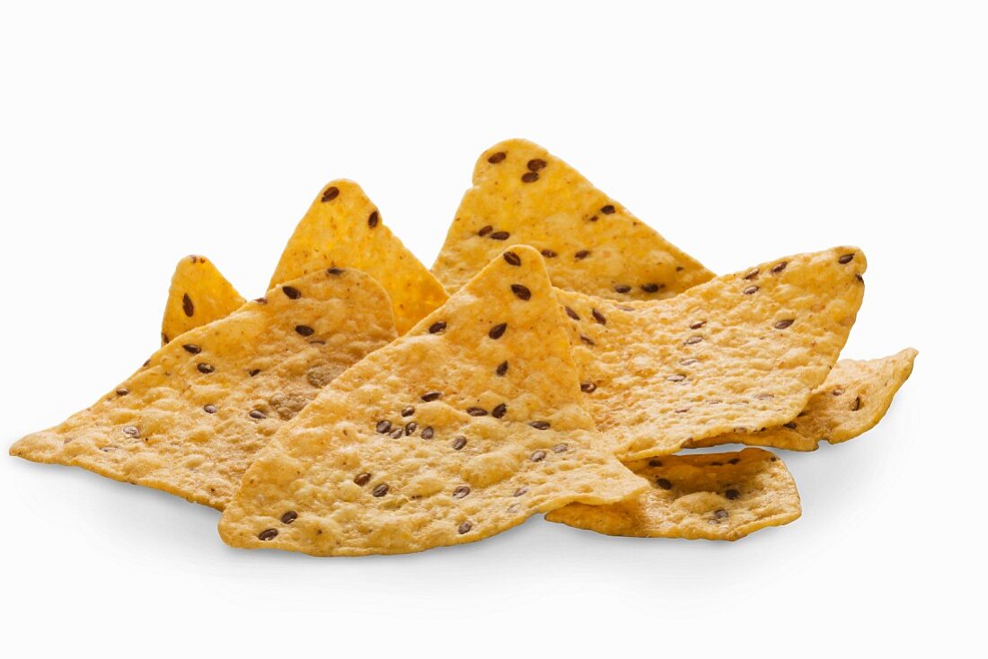 Multi-grain tortilla chips with flaxseeds on a white surface