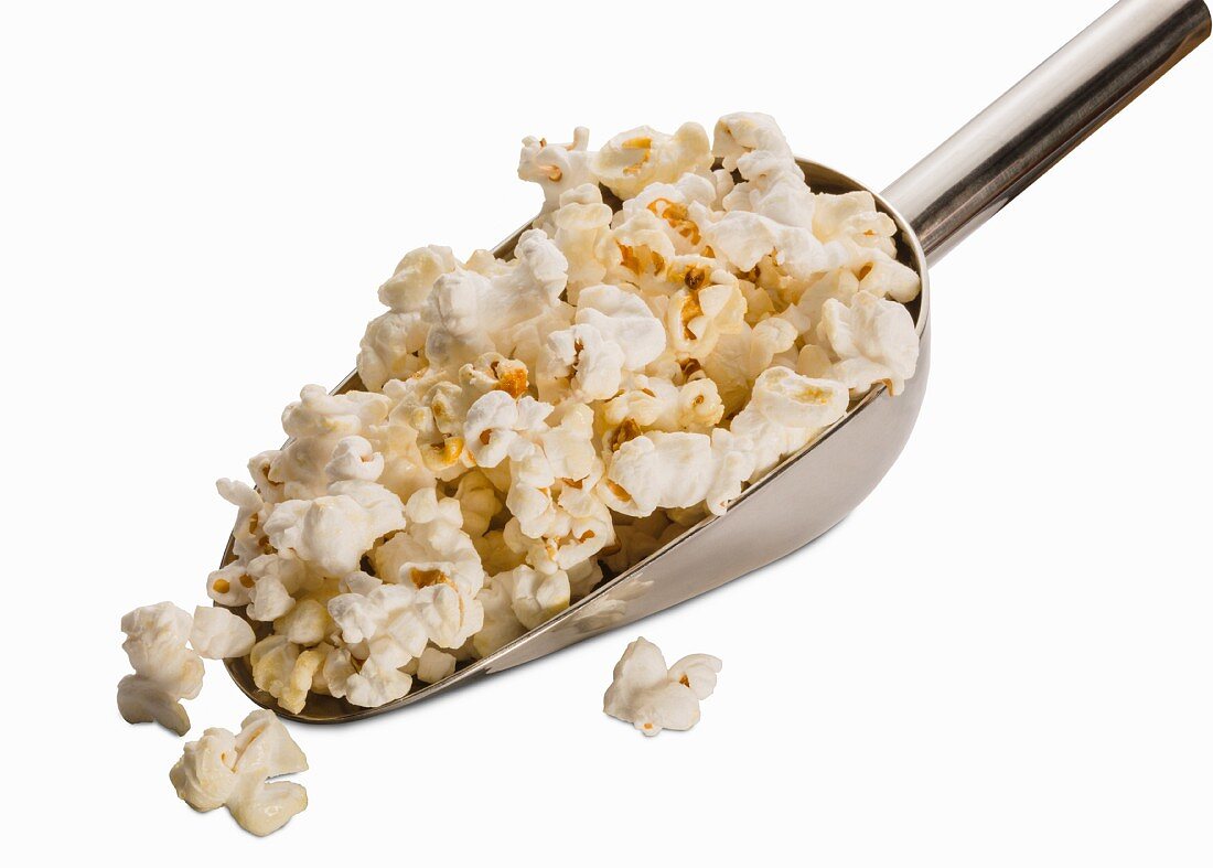 Popcorn auf Schaufel vor weißem Hintergrund (Nahaufnahme)