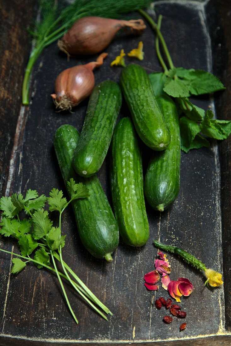 An arrangement of organic rose petals, coriander, cucumbers, shallots, dill and mint in a wooden crate