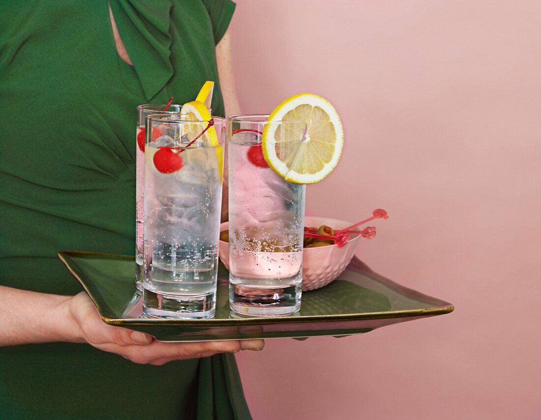 A woman holding a tray of Tom Collins cocktails