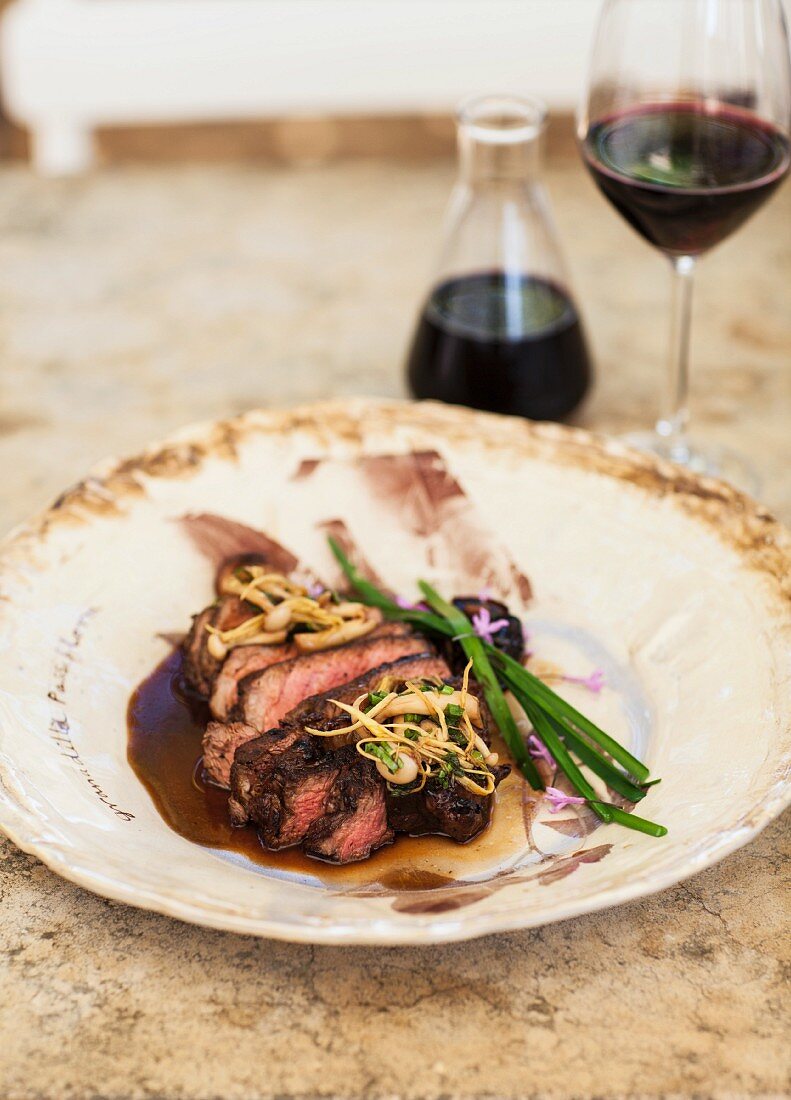 Rinderfilet in Scheiben auf Teller, im Hintergrund Karaffe und Glas mit Wein