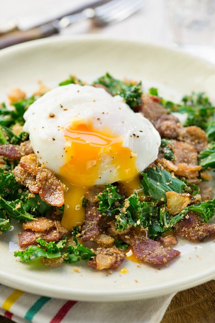 A poached egg with bacon and kale
