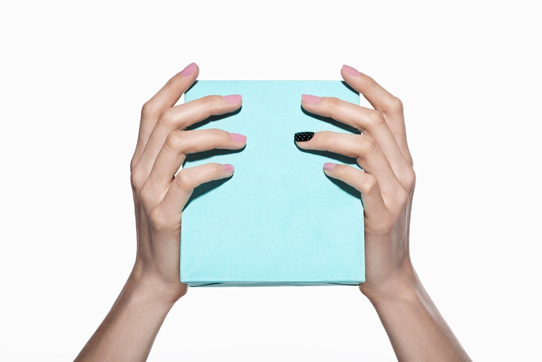 Frauenhände halten hellblaue Geschenkbox