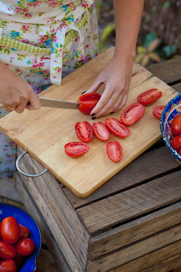 Frau schneidet Tomaten im Garten