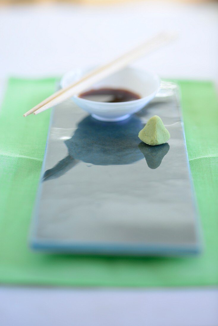 Soy sauce and wasabi paste on a shiny ceramic platter