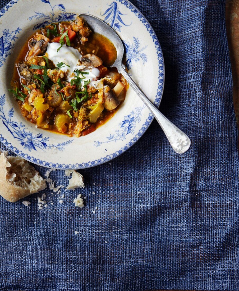 Lentil and vegetable stew with chopped parsley, sour cream and bread