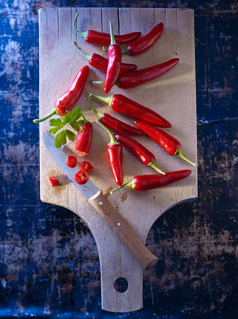 Rote Chilischoten auf Holzbrett mit glatter Petersilie