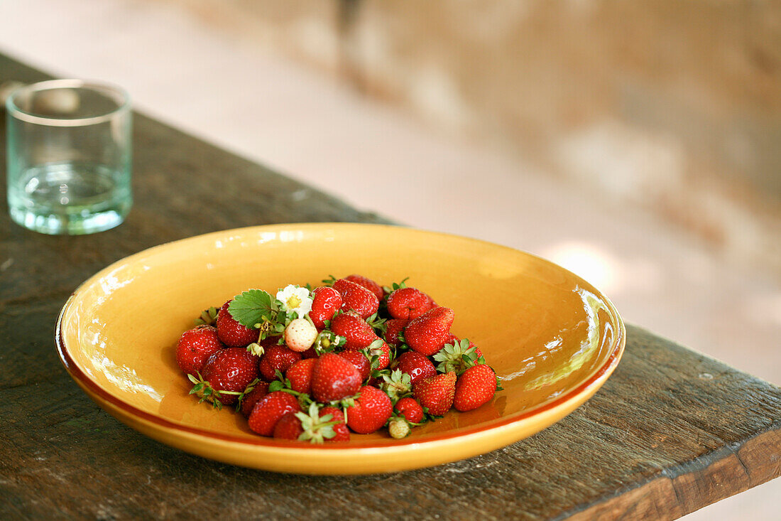 Frisch gepflückte Erdbeeren auf Teller auf Holztisch im Freien