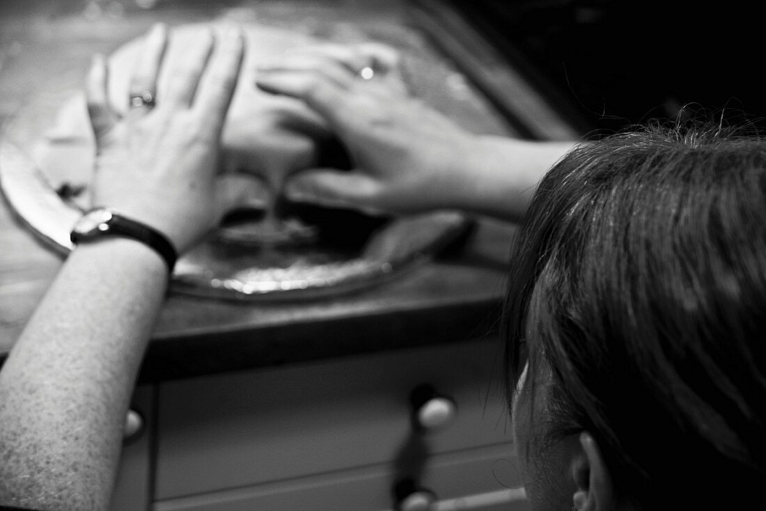 A person decorating wedding cake with fondant icing (black-and-white shot)