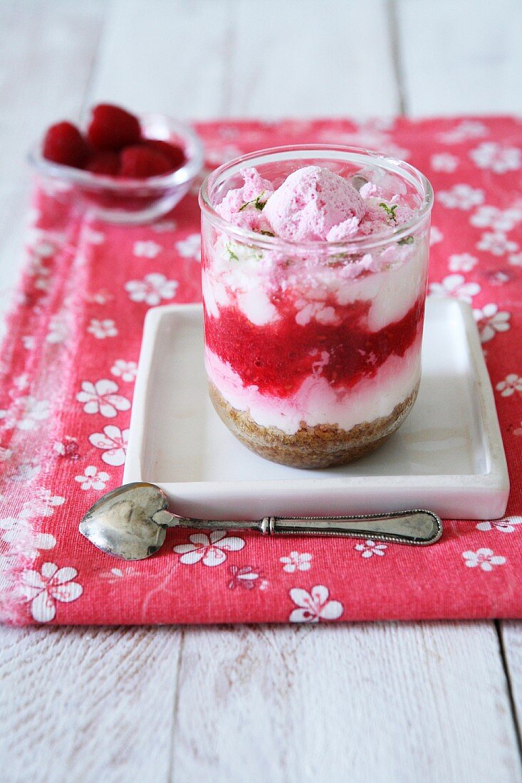 A layered dessrt with vanilla cream, biscuits, raspberries, pink meringues and lime zest