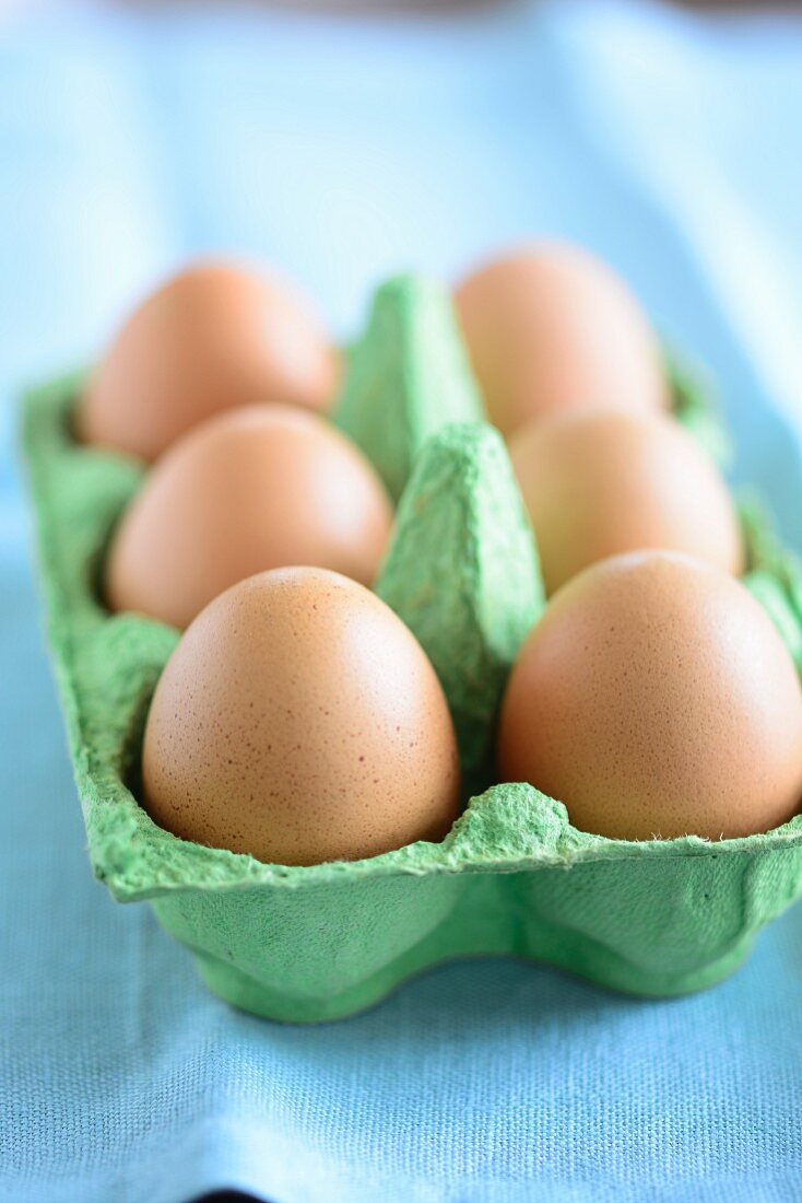 Six brown eggs in an egg box