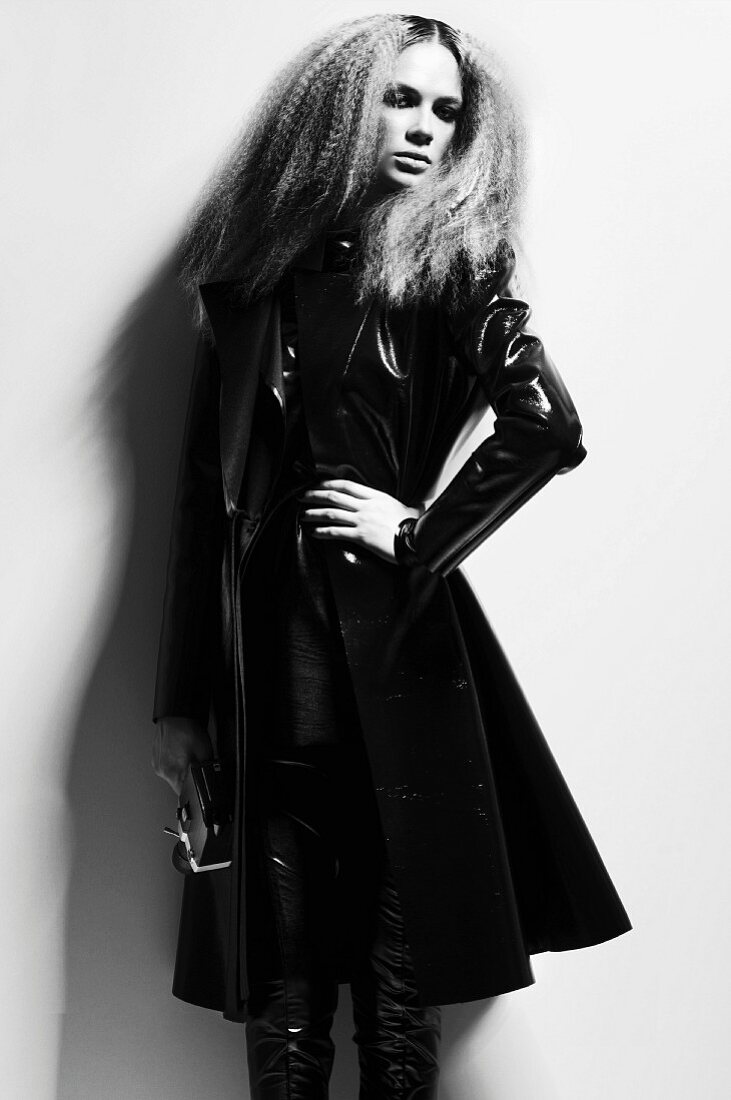 A young woman with crimped hair wearing a black patent leather coat (black-and-white shot)