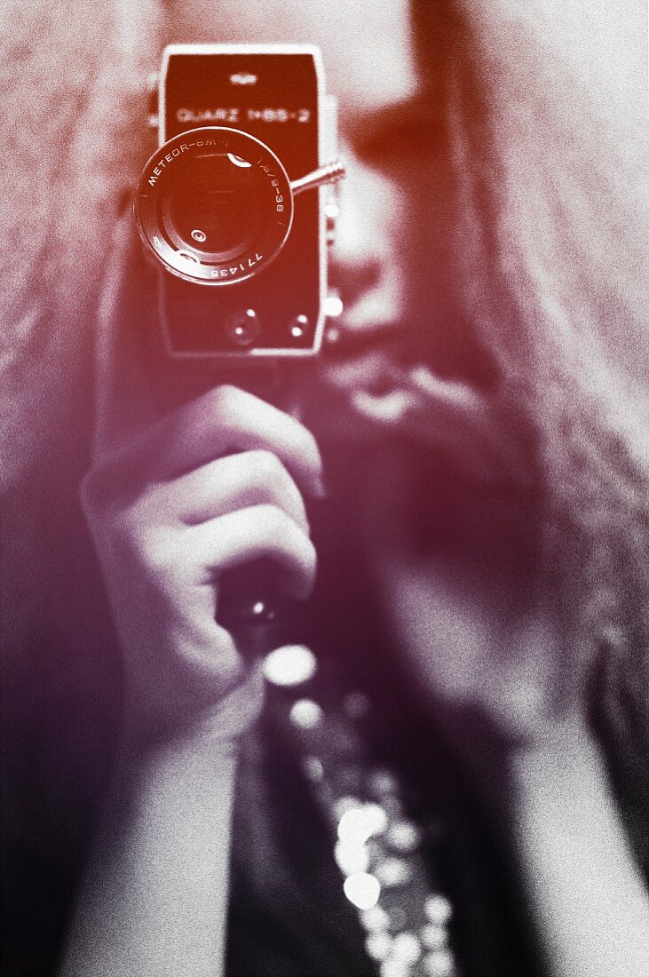 A young woman with crimped hair holding a video camera