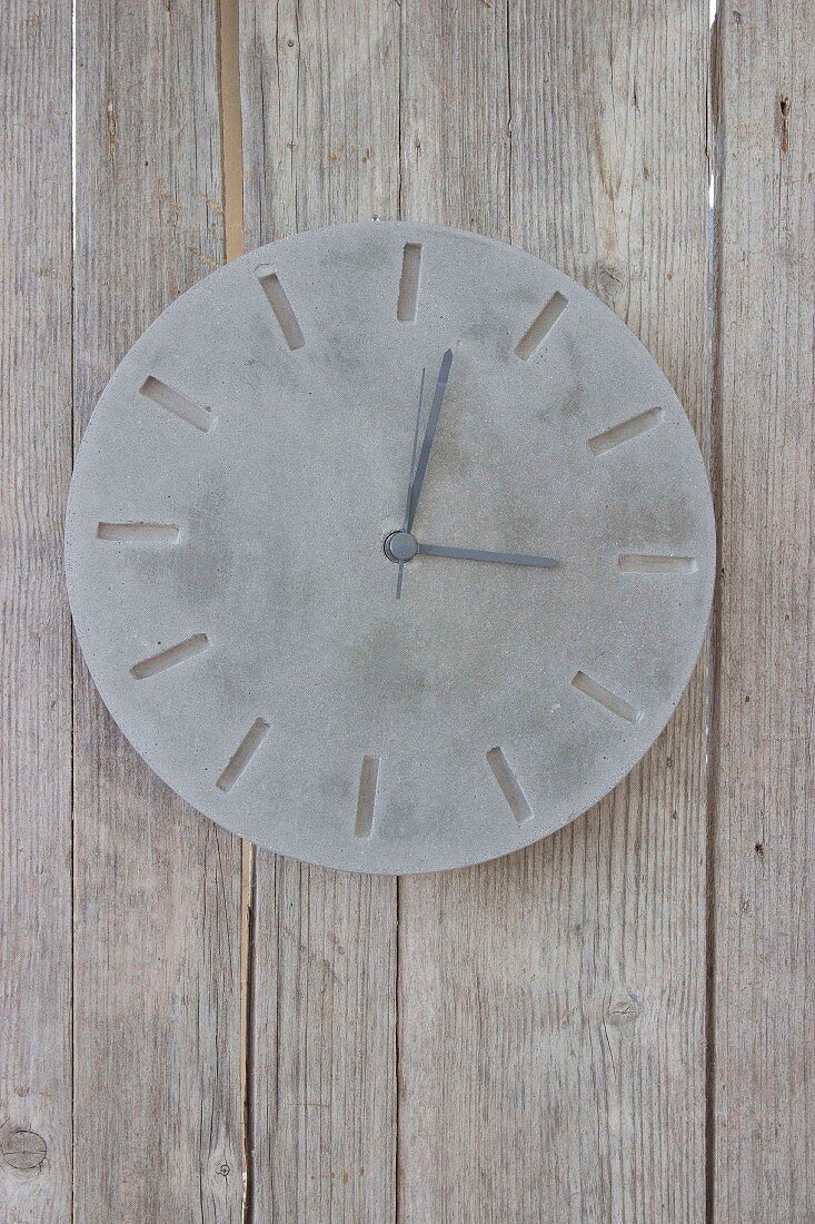 Hand-made concrete clock on board wall