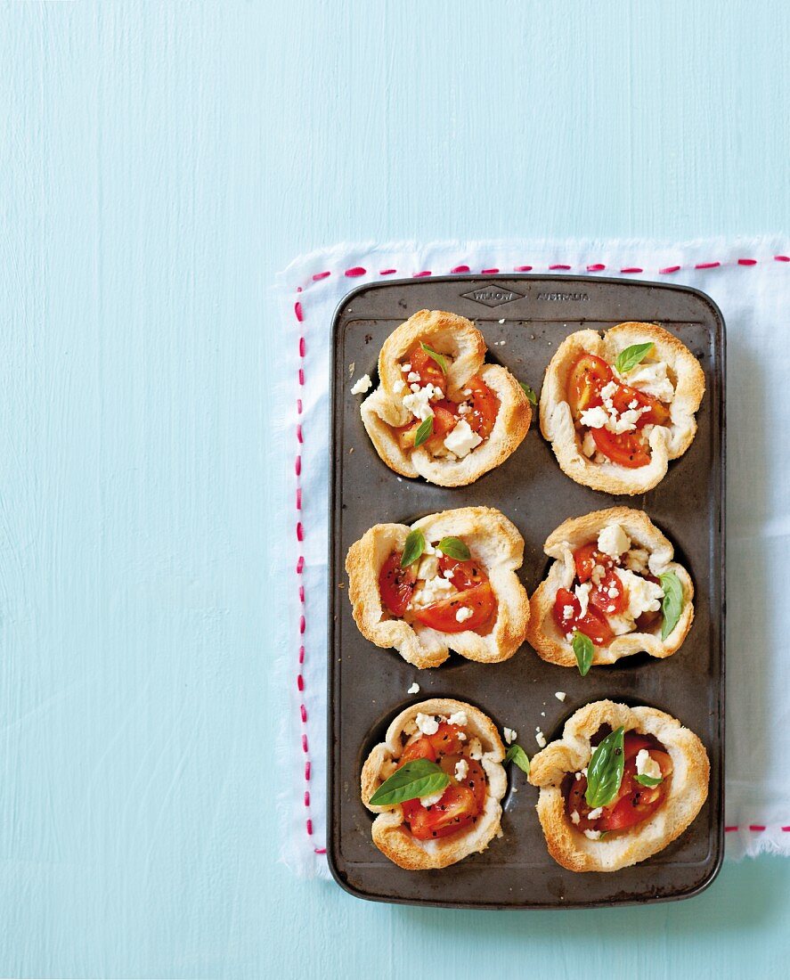 Bread bowls with tomato and feta cheese in a muffin tin