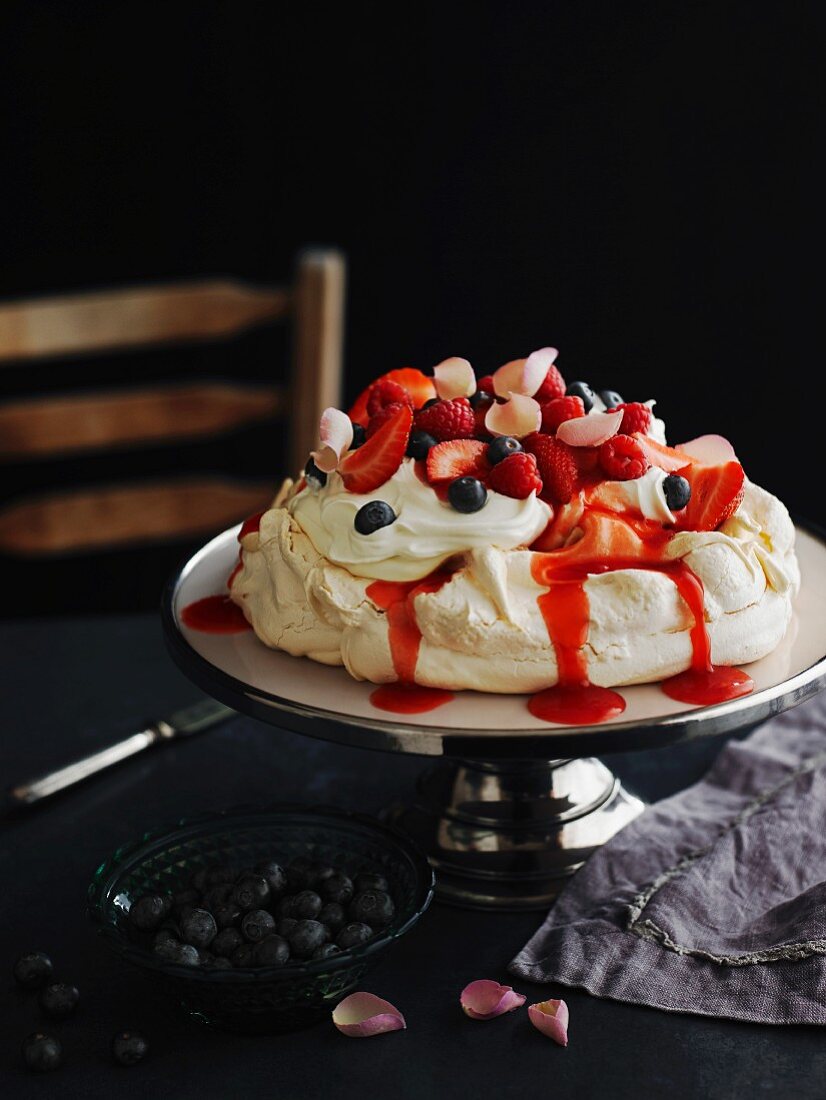 Pavlova mit Erdbeeren, Blaubeeren und Rosenblütenblättern