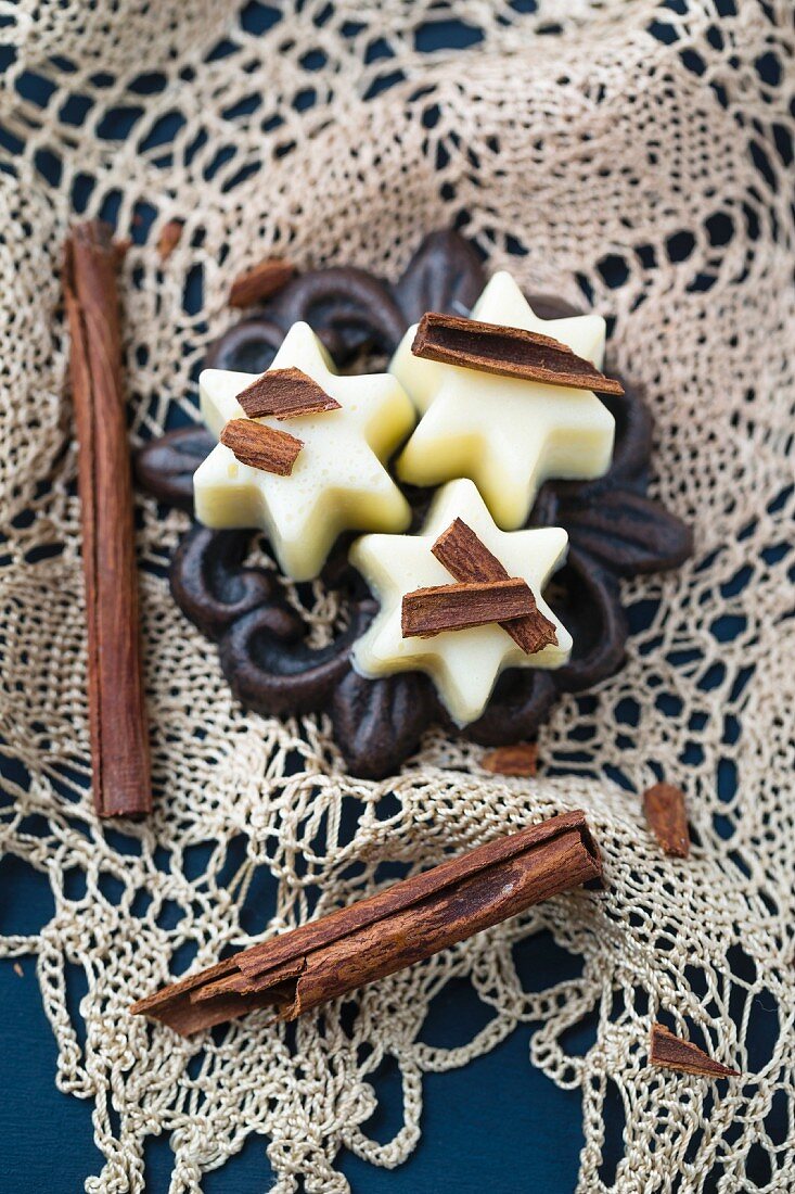 White chocolate pralines with cinnamon sticks on a crocheted doily