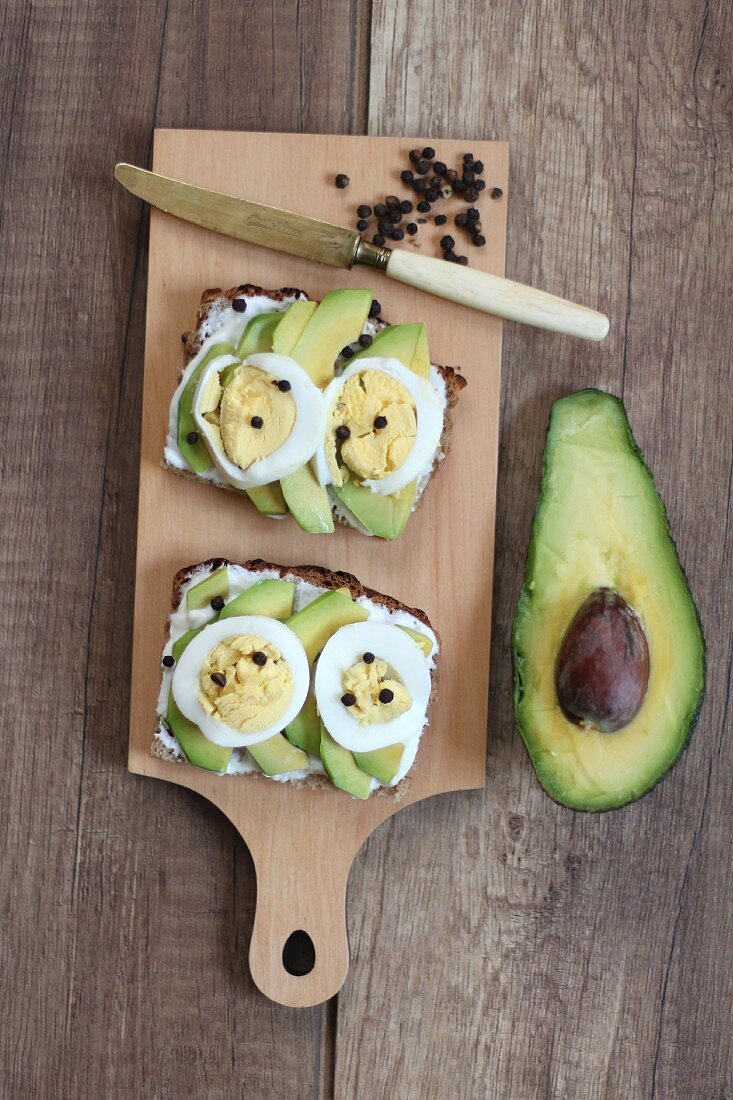 Slices of bread topped with avocado, egg and peppercorns