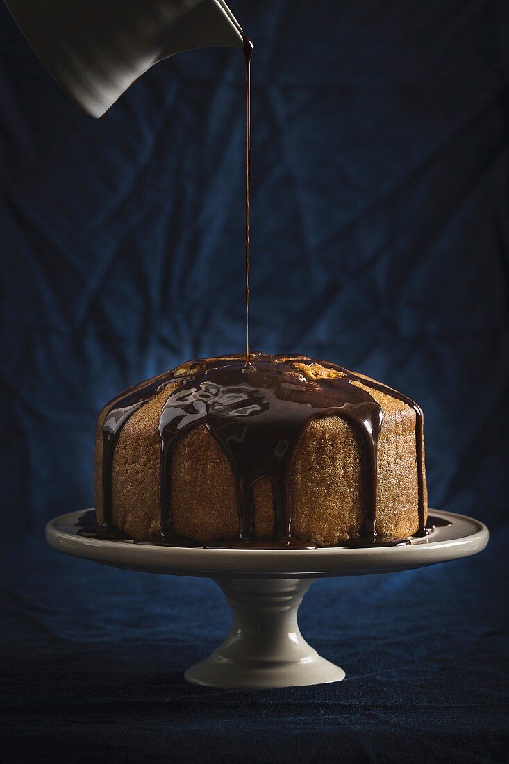 Chocolate glaze being poured over a cake