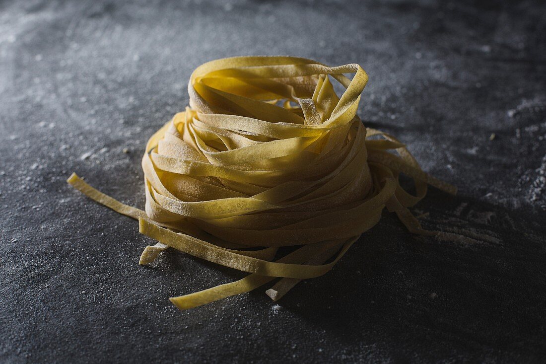 Homemade tagliatelle on a dark surface