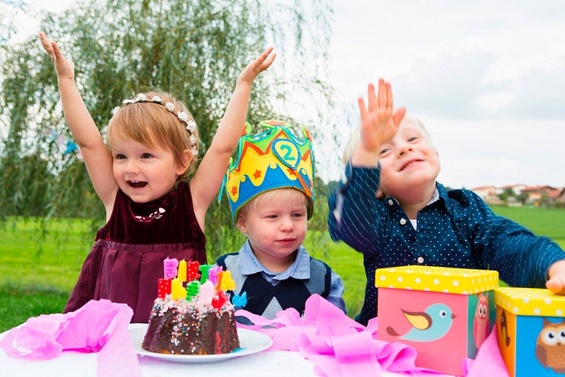 Three small children at a birthday party in a garden