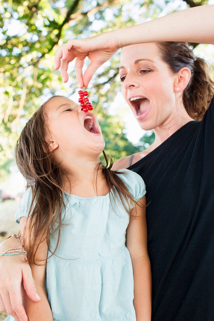 Mutter füttert Tochter mit roten Johannisbeeren