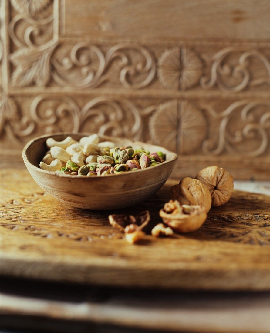 Cashew nuts, pistachios and walnuts in a wooden bowl and next to it
