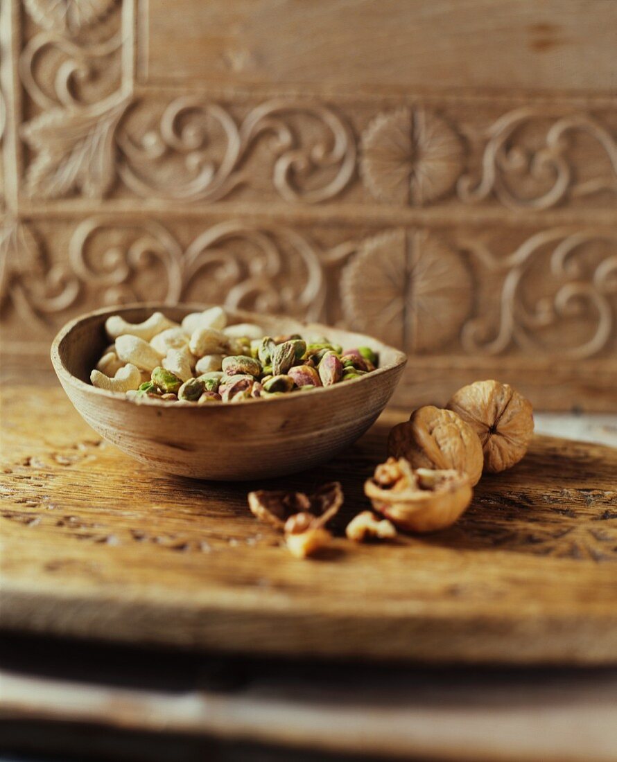 Cashewkerne, Pistazien und Walnüsse in Holzschale und daneben