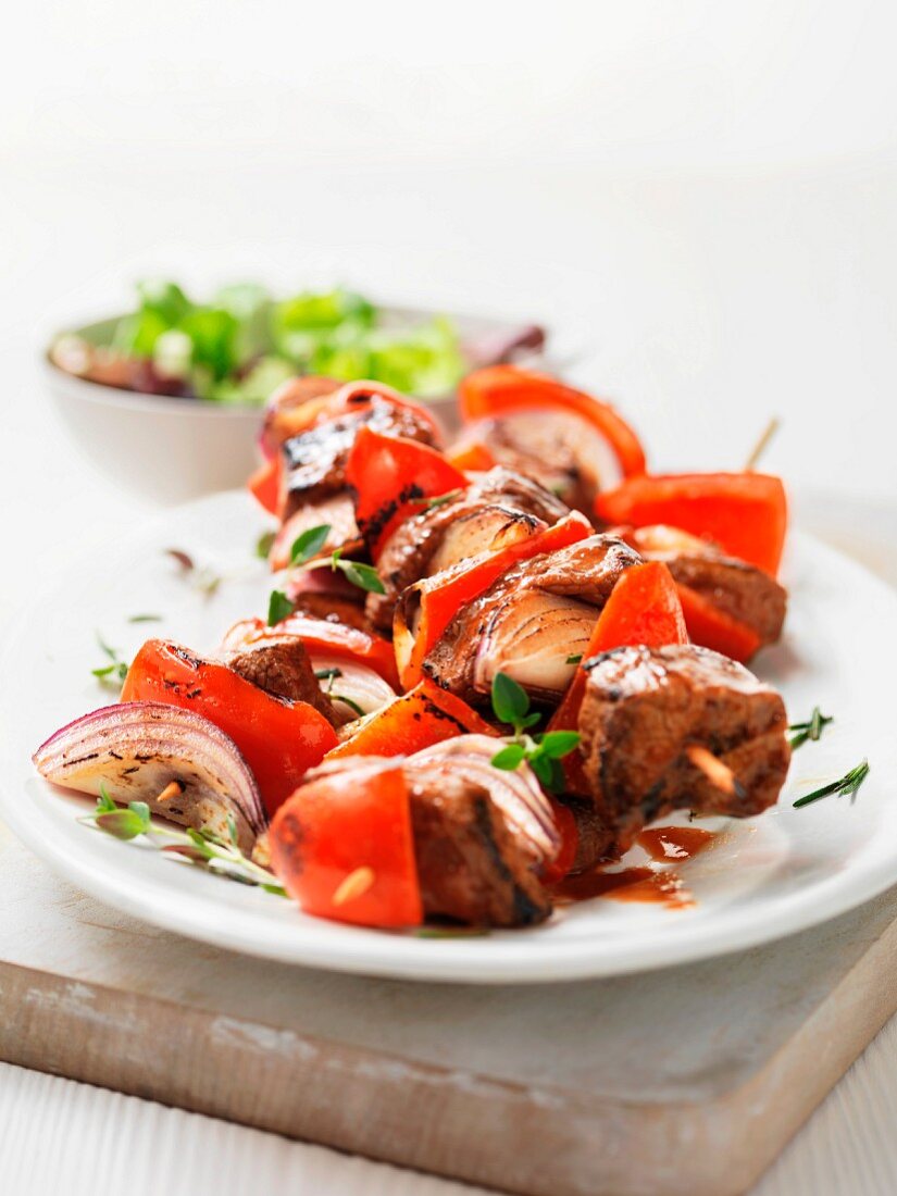 Fleischspieß vom Grill mit roten Zwiebeln, Paprika und Kräutern