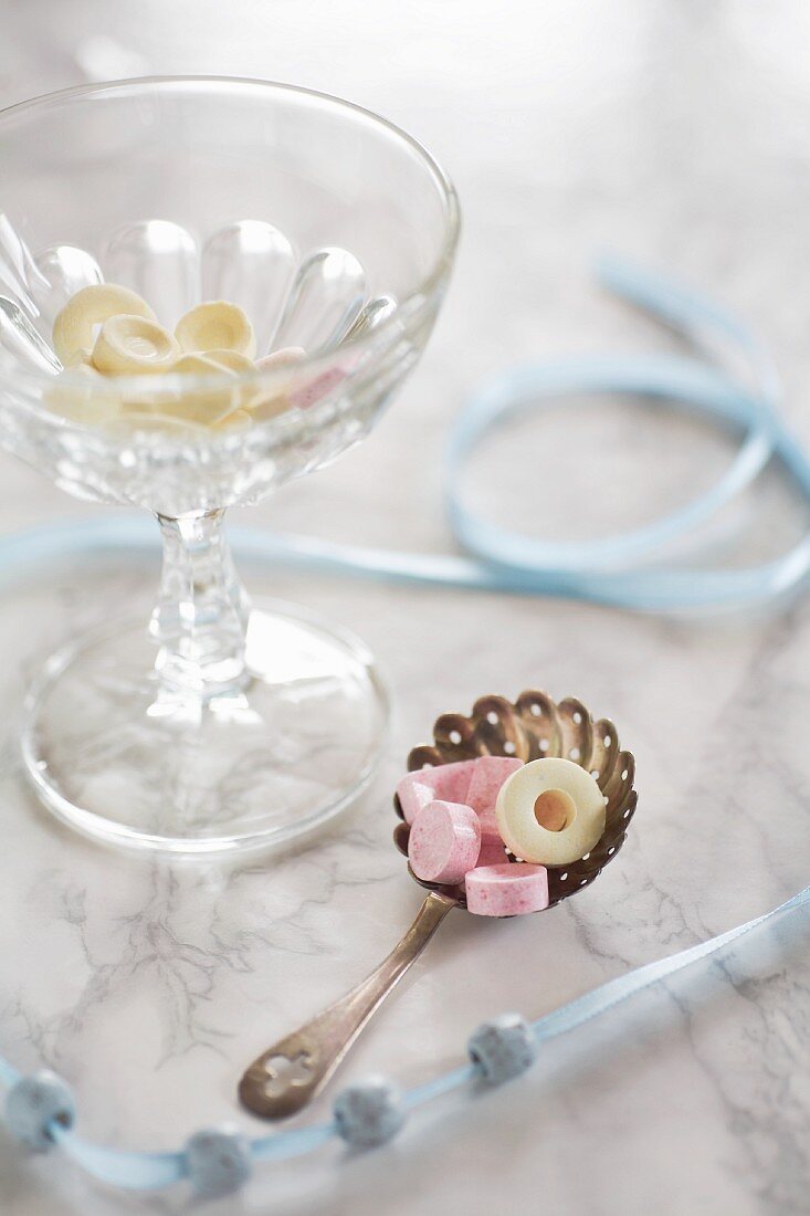An arrangement featuring a beaded ribbon and sweets in a glass bowl and on a silver spoon