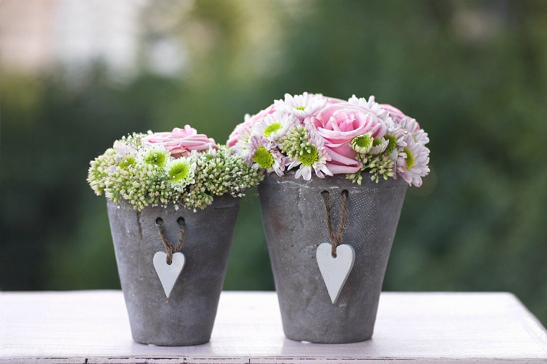 Flower arrangements with roses in grey pots with heart-shaped pendants