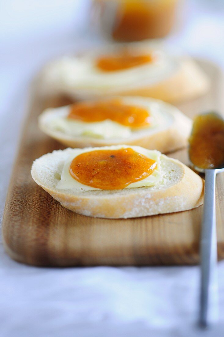 Slices of white bread topped with butter and apricot jam