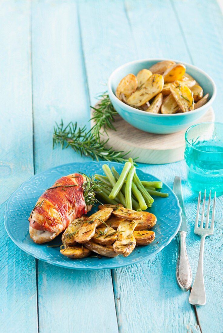 Chicken fillet wrapped in bacon served with baby potatoes, rosemary and green beans